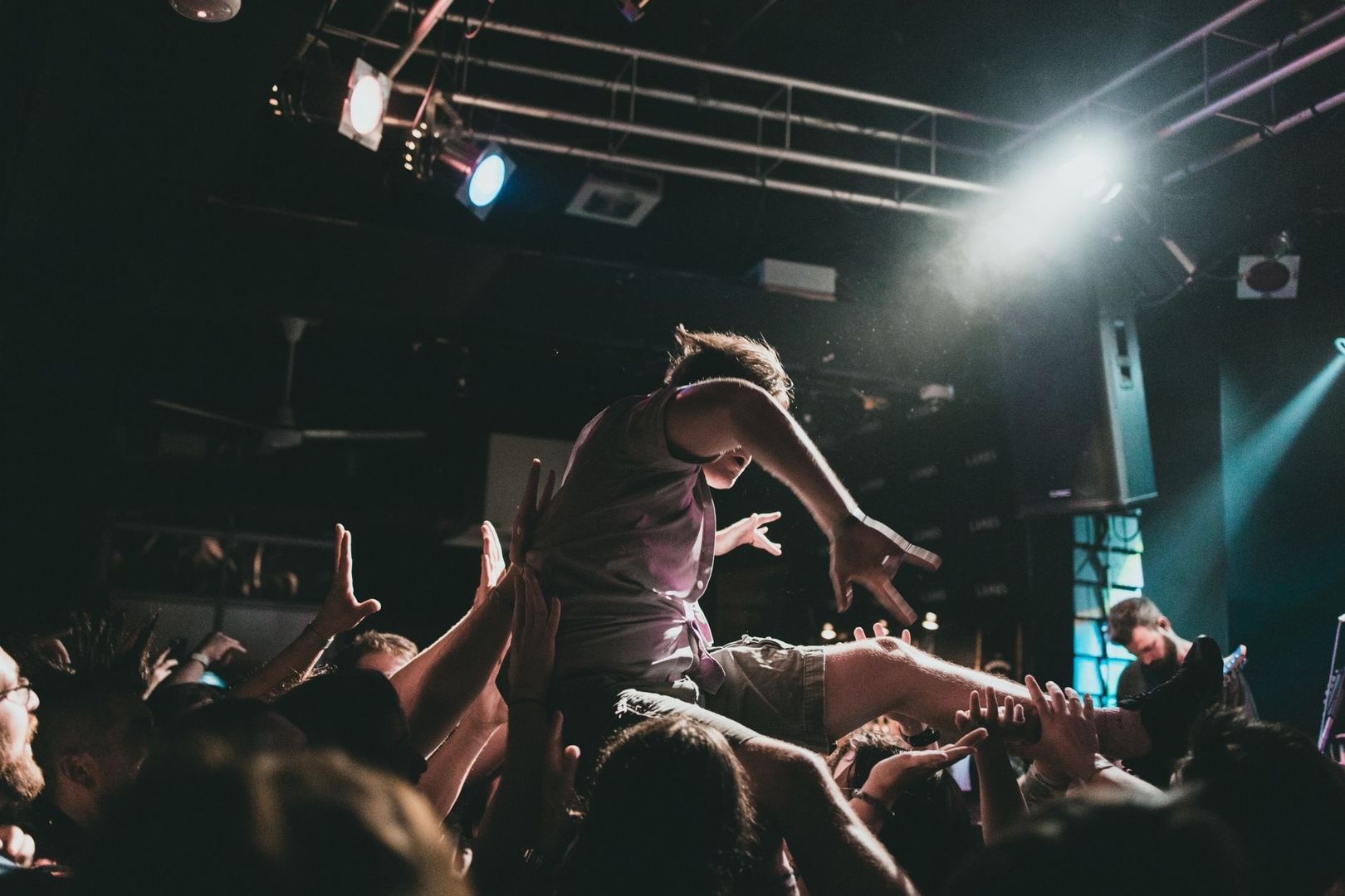 Crowdsurfende Person wird im Moshpit von vielen Händen getragen